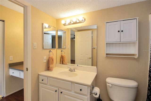 bathroom with vanity, toilet, and a textured ceiling