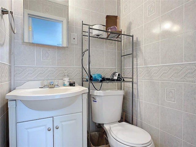 bathroom featuring vanity, toilet, and tile walls