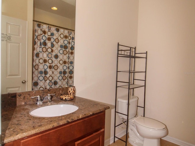 full bath featuring toilet, vanity, and baseboards