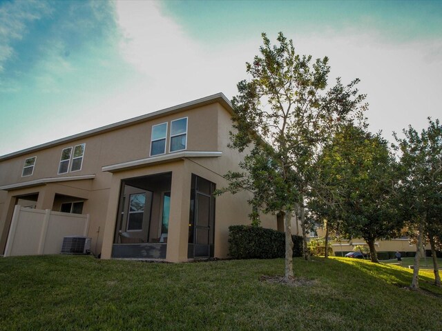 back of property with a lawn, fence, cooling unit, and stucco siding