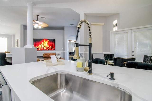 kitchen with decorative columns, sink, pendant lighting, and ceiling fan