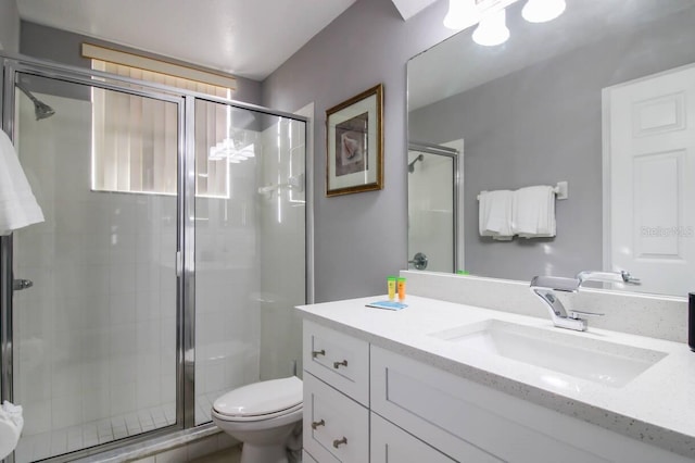 bathroom with vanity, toilet, and a shower with door