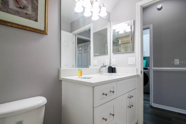 bathroom featuring vanity, toilet, washer / dryer, and wood-type flooring