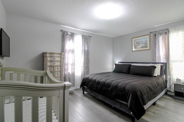 bedroom with multiple windows, light hardwood / wood-style flooring, and a textured ceiling