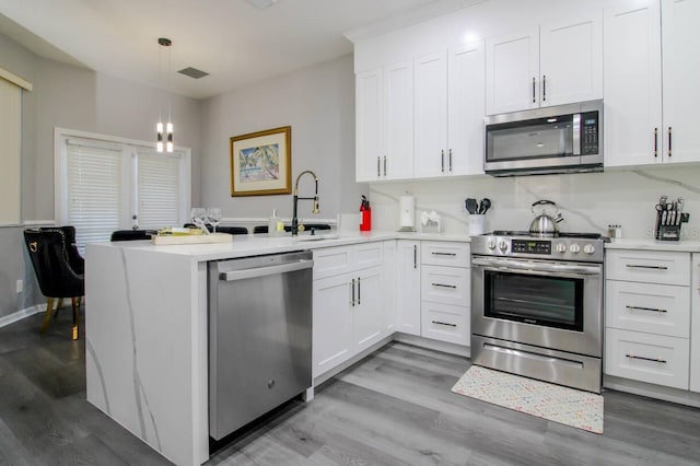 kitchen with white cabinetry, pendant lighting, stainless steel appliances, and kitchen peninsula