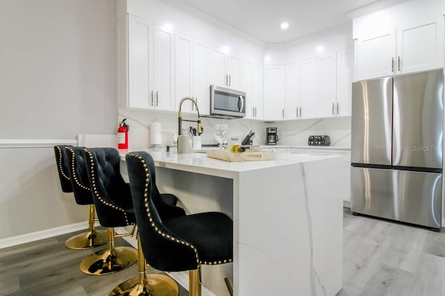 kitchen with white cabinetry, appliances with stainless steel finishes, a breakfast bar area, and kitchen peninsula