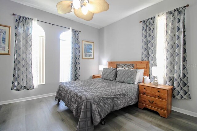 bedroom featuring multiple windows, dark hardwood / wood-style floors, and ceiling fan