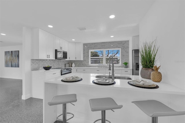 kitchen featuring appliances with stainless steel finishes, white cabinets, and a kitchen breakfast bar