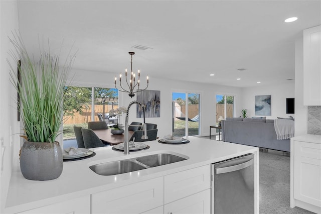 kitchen featuring dishwasher, sink, white cabinets, decorative backsplash, and hanging light fixtures