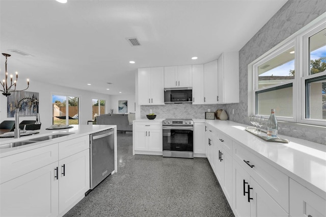 kitchen with appliances with stainless steel finishes, white cabinetry, sink, decorative backsplash, and hanging light fixtures