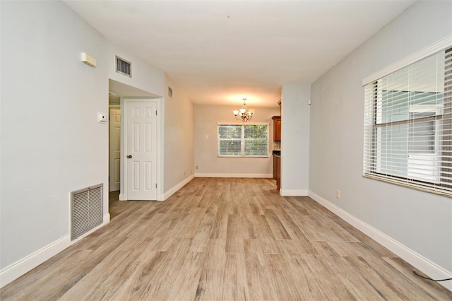 unfurnished room with an inviting chandelier and light hardwood / wood-style flooring