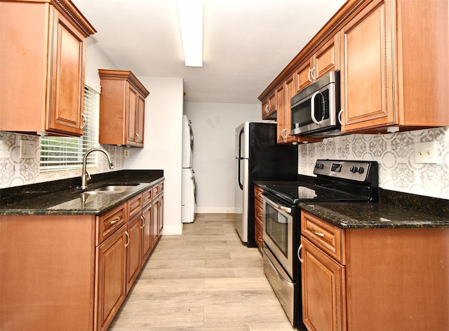 kitchen with tasteful backsplash, appliances with stainless steel finishes, sink, and dark stone countertops