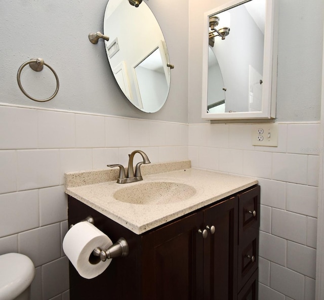 bathroom with vanity, tile walls, and toilet