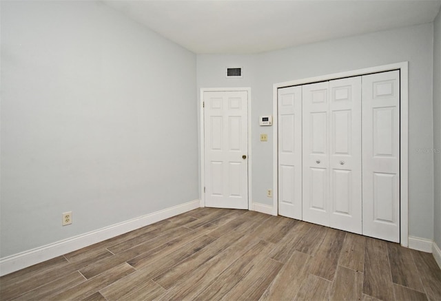 unfurnished bedroom with wood-type flooring and a closet