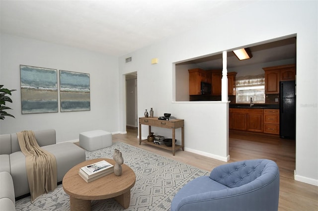 living room featuring sink and light hardwood / wood-style flooring