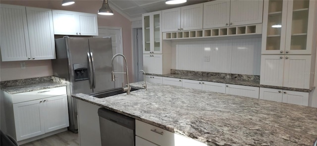 kitchen with pendant lighting, dishwasher, white cabinetry, light stone countertops, and light hardwood / wood-style floors