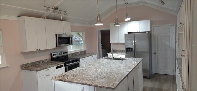 kitchen featuring vaulted ceiling, appliances with stainless steel finishes, an island with sink, pendant lighting, and white cabinets