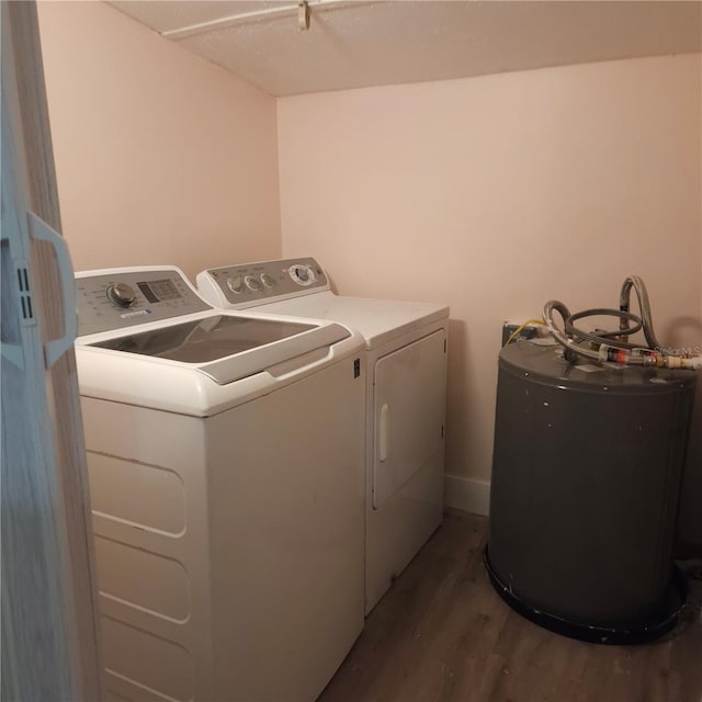 laundry area featuring water heater, dark hardwood / wood-style flooring, and washer and dryer