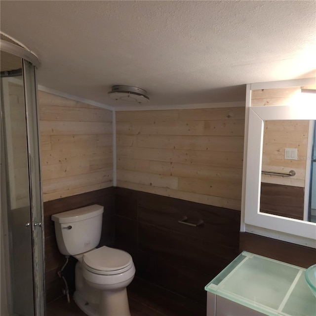 bathroom featuring toilet, a textured ceiling, and wood walls