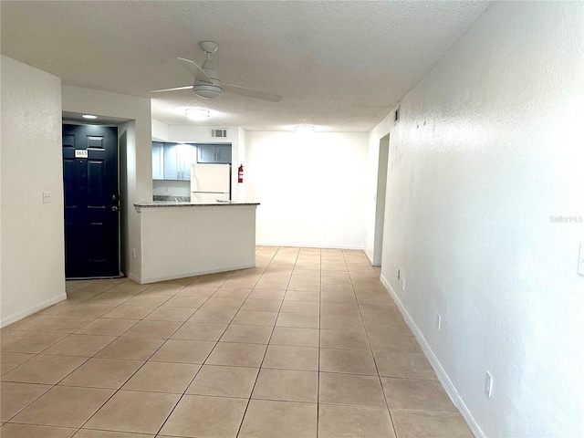 interior space featuring light tile patterned floors, a textured ceiling, and ceiling fan