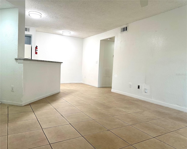 spare room with indoor bar, light tile patterned floors, and a textured ceiling