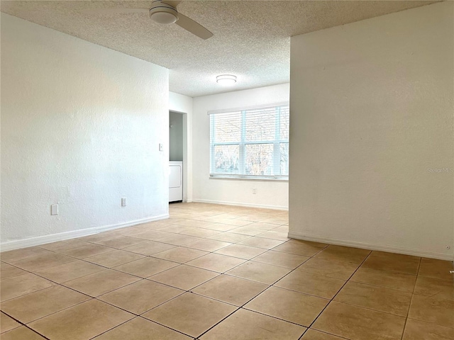 tiled empty room featuring ceiling fan, washer / clothes dryer, and a textured ceiling