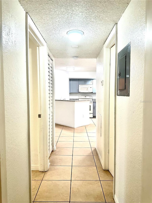 hallway featuring light tile patterned flooring, electric panel, and a textured ceiling