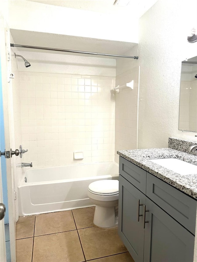 full bathroom featuring vanity, tiled shower / bath combo, tile patterned floors, and toilet