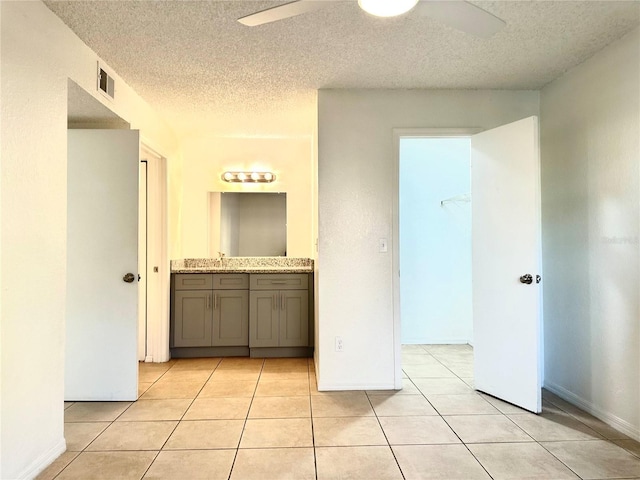 interior space featuring light tile patterned floors, sink, ceiling fan, connected bathroom, and a textured ceiling