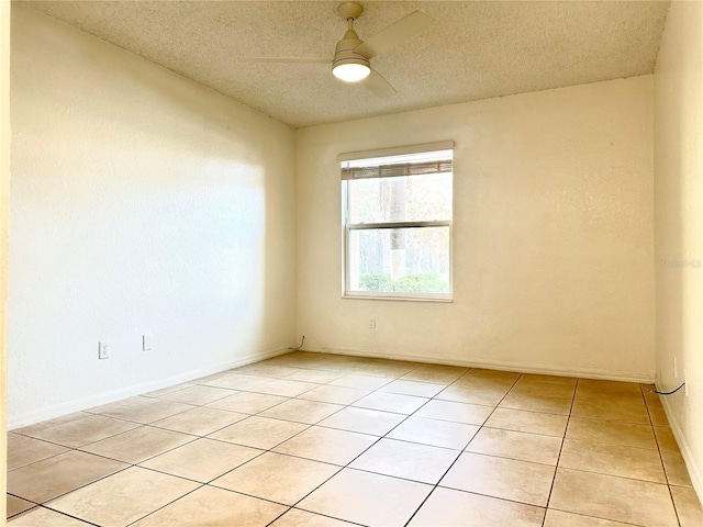 empty room featuring ceiling fan, light tile patterned floors, and a textured ceiling