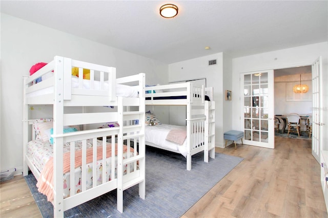 bedroom with an inviting chandelier, hardwood / wood-style floors, french doors, and a textured ceiling