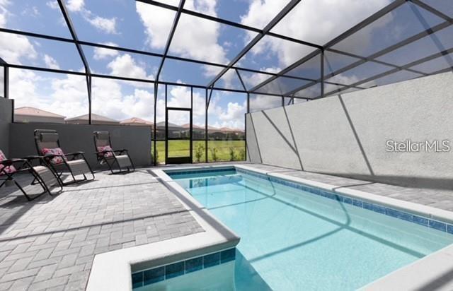 view of pool with a patio area and glass enclosure