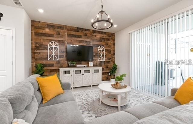 living room with an inviting chandelier and wooden walls