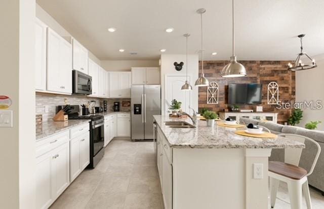 kitchen featuring an island with sink, appliances with stainless steel finishes, sink, and white cabinets