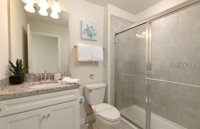 bathroom featuring vanity, a shower with shower door, a chandelier, and toilet