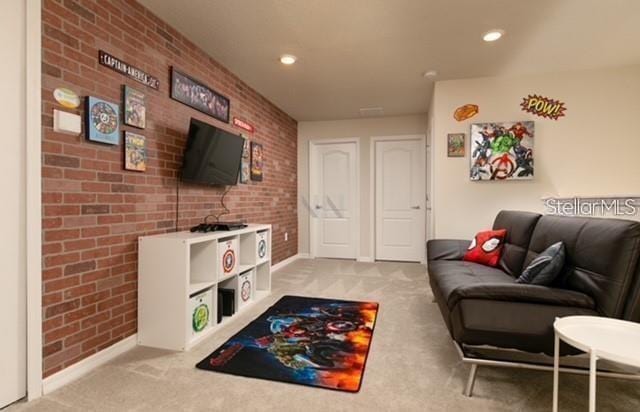 carpeted living room featuring brick wall