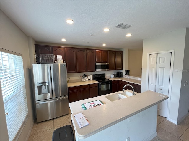 kitchen with sink, dark brown cabinets, light tile patterned flooring, and appliances with stainless steel finishes