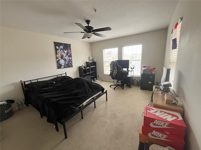 bedroom with ceiling fan, carpet, and a textured ceiling