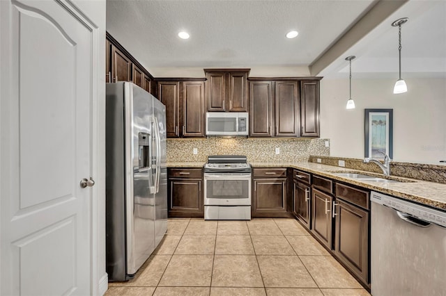 kitchen featuring sink, light stone counters, decorative light fixtures, light tile patterned floors, and stainless steel appliances