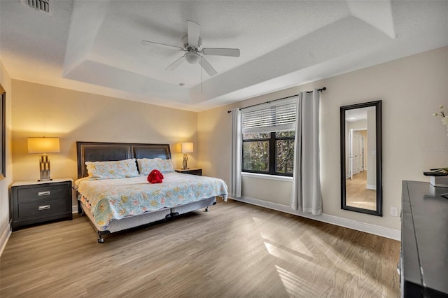 bedroom featuring a tray ceiling, light hardwood / wood-style flooring, and ceiling fan