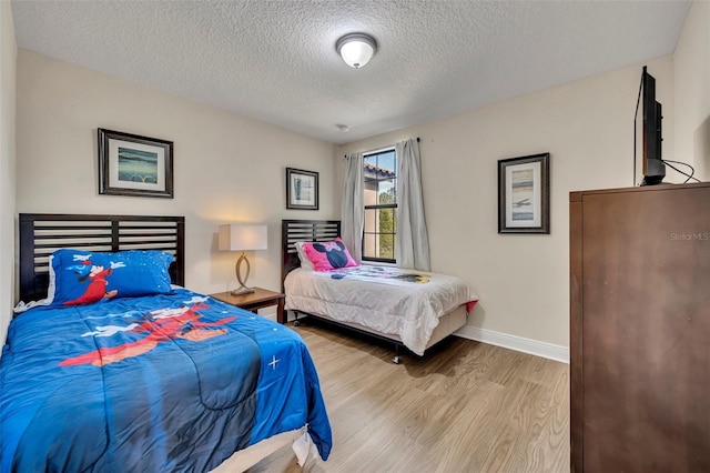 bedroom with a textured ceiling and light wood-type flooring