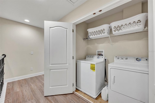 laundry area with separate washer and dryer and light hardwood / wood-style flooring