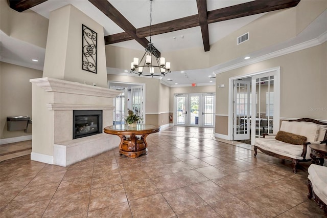 tiled living room featuring a premium fireplace, a notable chandelier, ornamental molding, french doors, and beamed ceiling