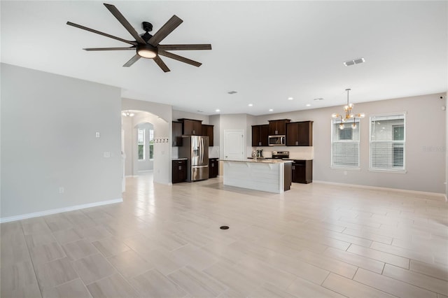 unfurnished living room featuring ceiling fan with notable chandelier