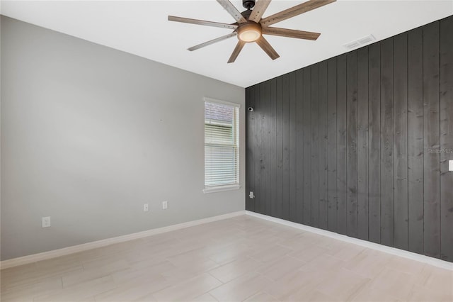 unfurnished room with ceiling fan and wood walls