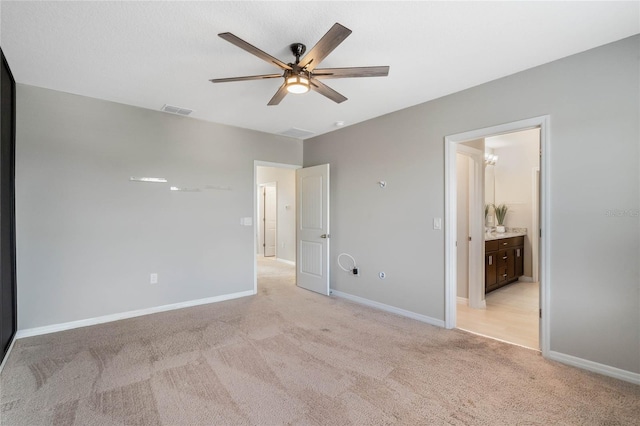 unfurnished bedroom featuring light carpet, connected bathroom, and ceiling fan