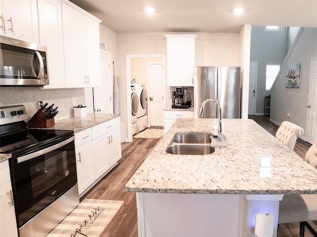 kitchen with stainless steel appliances, sink, washer and dryer, and a center island with sink