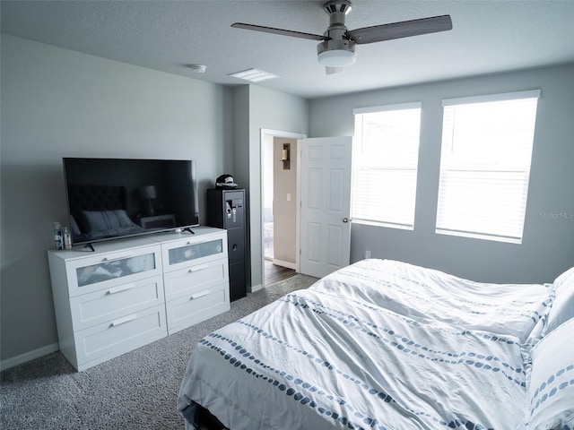 bedroom with dark colored carpet, a textured ceiling, and ceiling fan