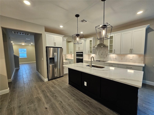 kitchen with sink, a center island with sink, stainless steel fridge, pendant lighting, and white cabinets