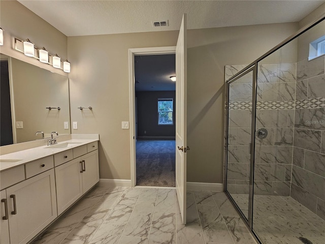 bathroom featuring tiled shower, vanity, and a textured ceiling